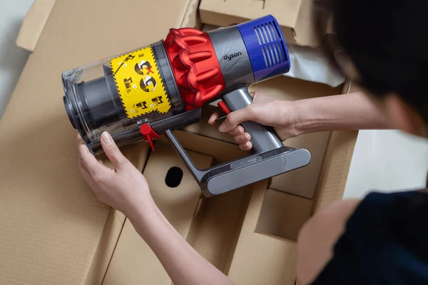 Dyson V10 cordless vacuum being held in somebody's hands, Shutterstock image.